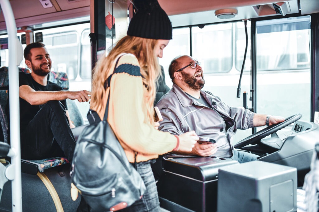 Busfahrer scherzt mit junger Frau.
